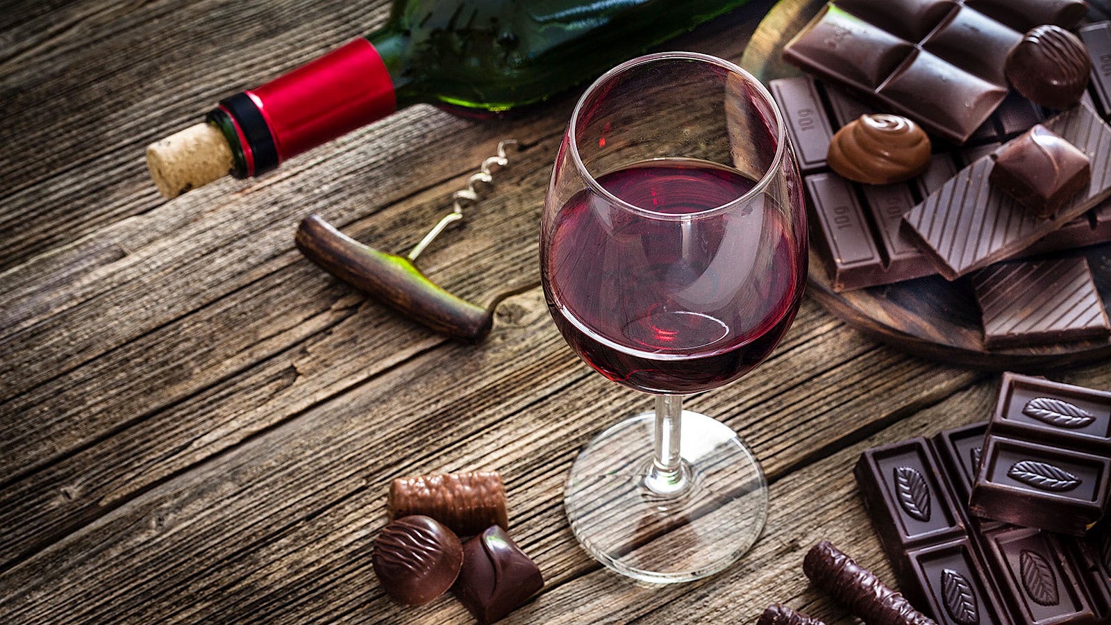 Chocolates, a corkscrew, a bottle and a glass of red wine