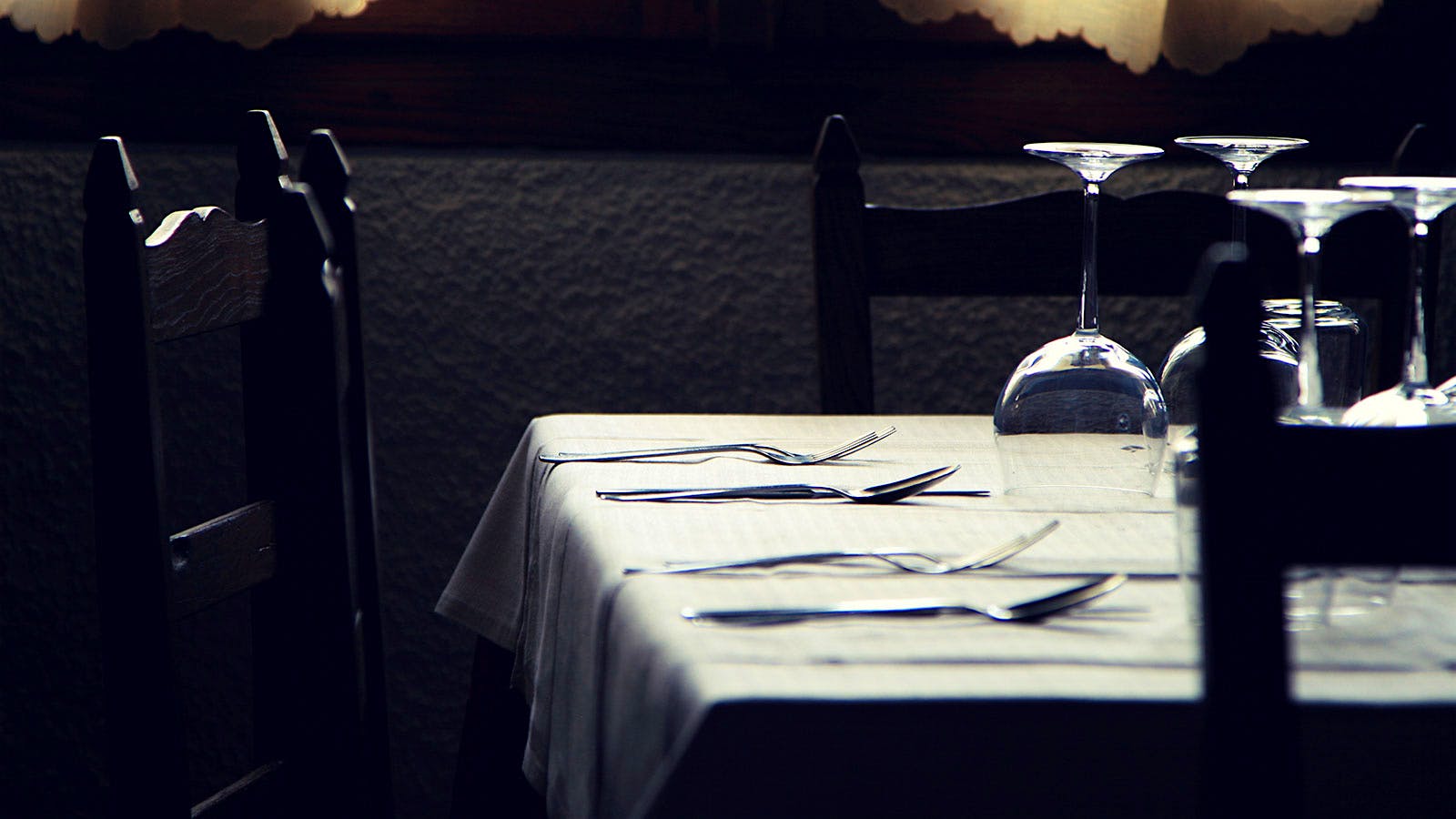 Empty wineglasses rest upside down on a table.