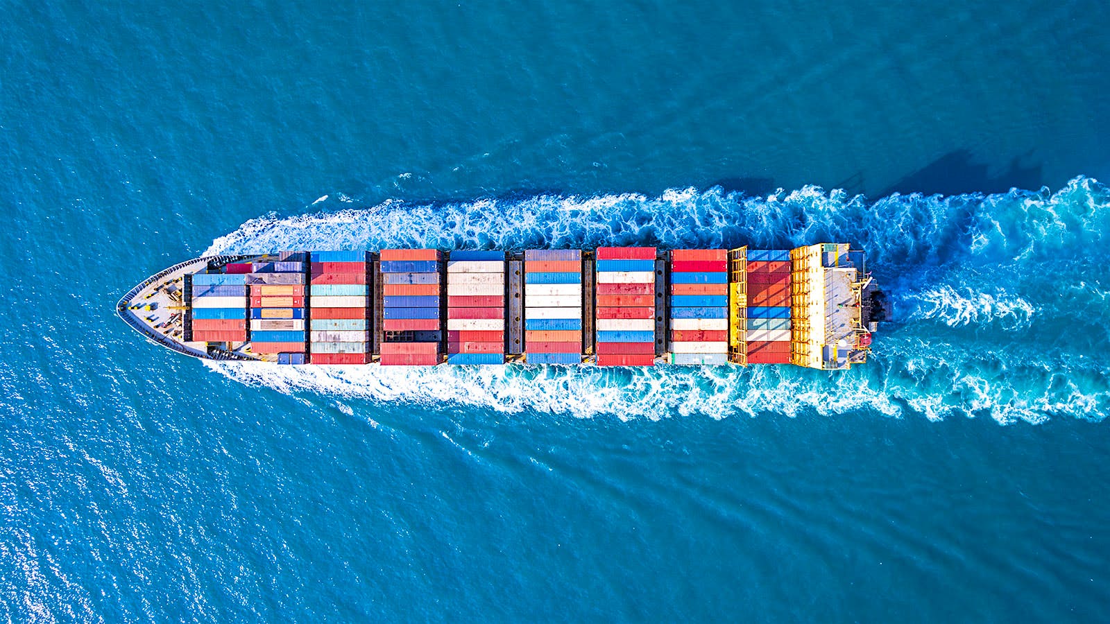 A container ship steams through water.