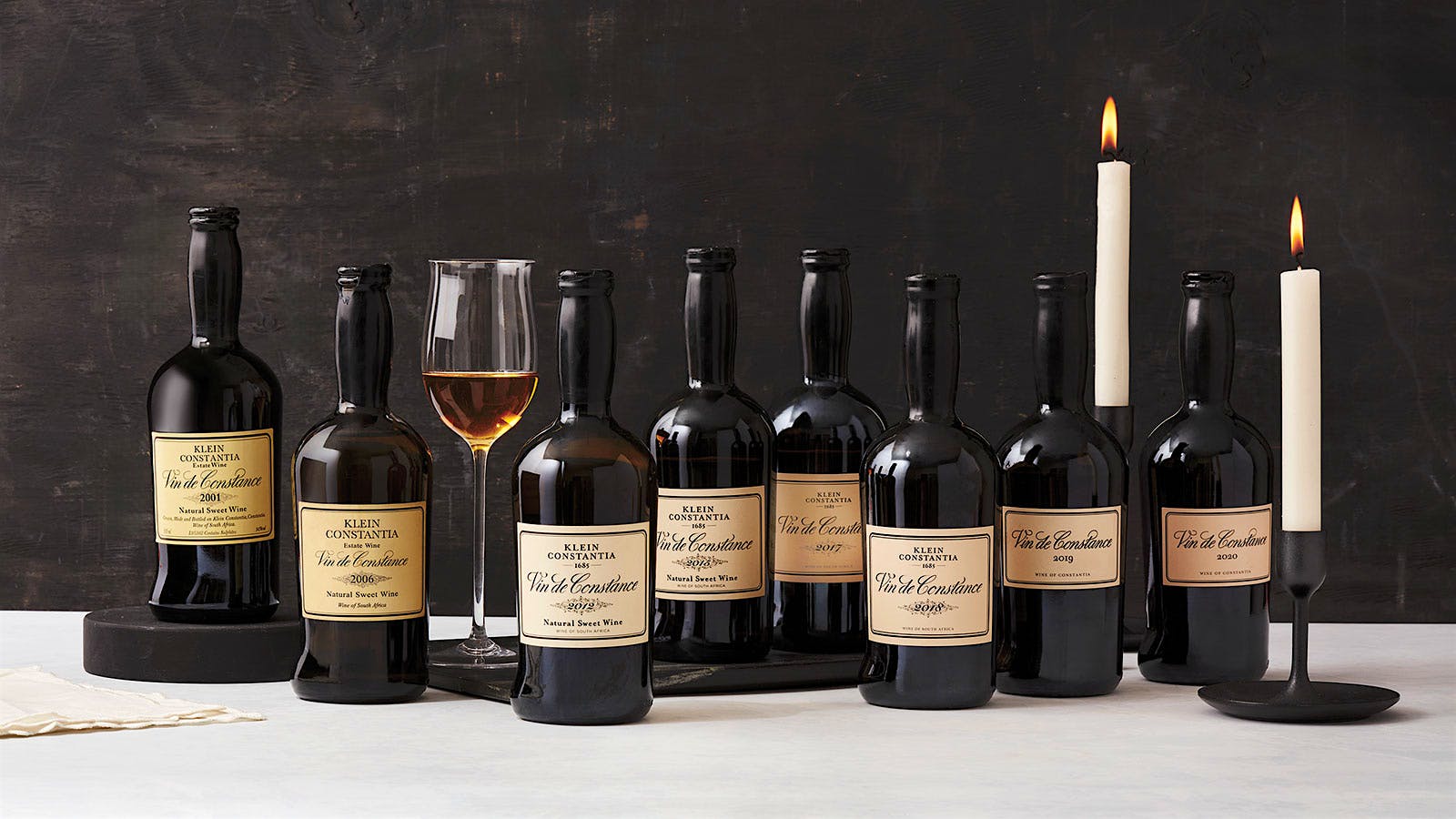 Eight bottles of Klein Constantia Vin de Constance dessert wines with a glass poured in the center