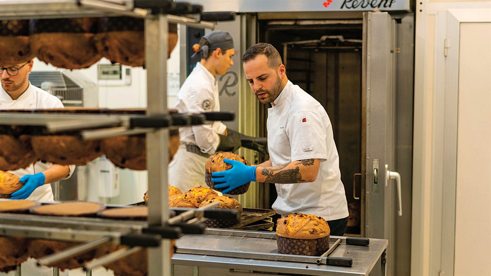 Bakers at Olivieri 1882 transfer fresh baked panettone from the oven to cooling racks.