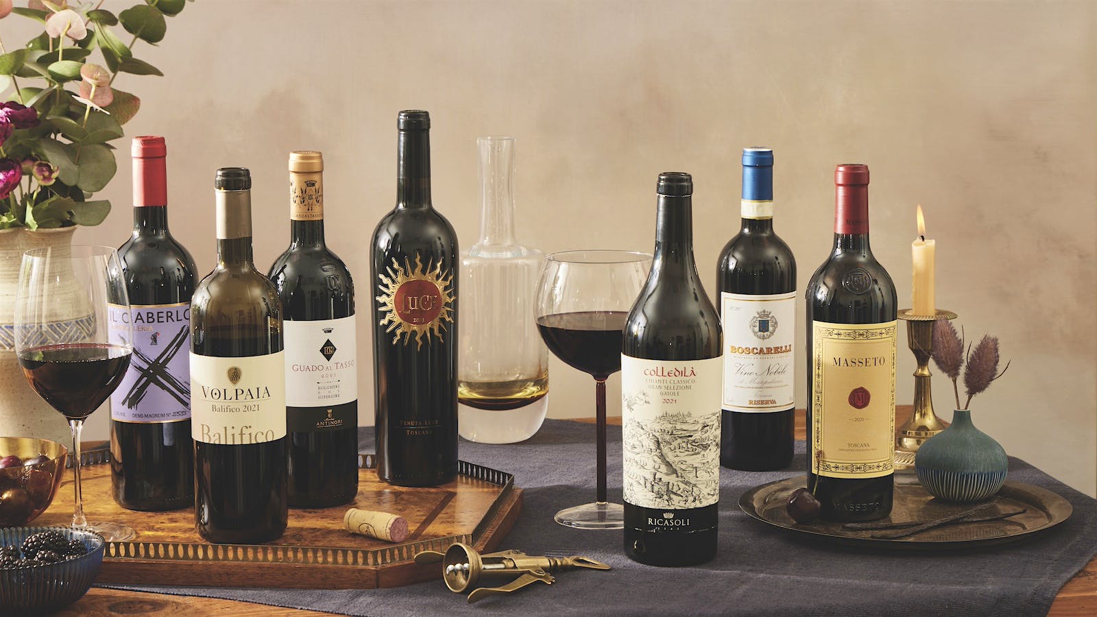 The top-rated wines of Tuscany from the 2021 vintage are displayed alongside poured glasses on a table.