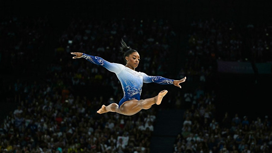 Simone Biles leaps on the balance beam during the Paris Olympics; she's invited some wine lovers to leap for joy on the sidelines of a Chicago Bears game.